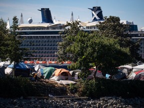 Tents and people are seen at a homeless encampment at CRAB Park as the Celebrity Cruises vessel Celebrity Eclipse is docked at port in Vancouver on Sunday, Aug. 14, 2022.