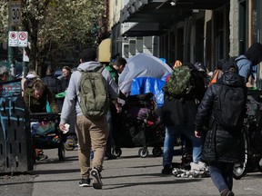 Tents are seen on the sidewalk as people walk in the Downtown Eastside of Vancouver on April 3. On Christmas Day, Trey Helten, a manager at Vancouver's Overdose Prevention Society, was still hard at work, dealing with the latest victim of what he says is a seasonal spike in the drug toxicity crisis.