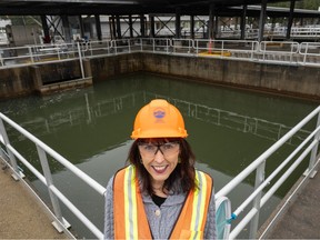 Metro Vancouver's Linda Parkinson in hard hat and safety vest stands in front of a pool of green water at the Seymour Capilano Filtration Plant.