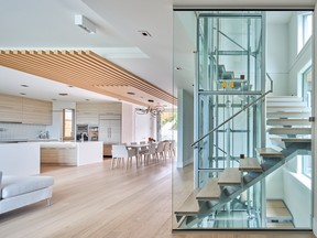 The staircase wraps around the glass-encased elevator and offers access to all three floors of the home. Its transparent quality integrates rather than dominates in the space.