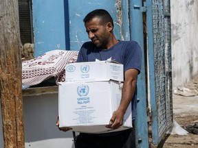 A Palestinian man transports boxes of food outside an aid distribution centre run by the United Nations Relief and Works Agency (UNRWA) in the central Gaza Strip refugee camp of Bureij, in 2019.