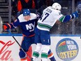 Canucks defenceman Noah Juulsen slams Simon Holmstrom of the Islanders during Tuesday's game at the UBS Arena.