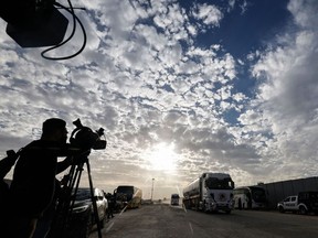 Media representatives work as a truck carrying humanitarian aid from the United Nations Relief and Works Agency for Palestine Refugees (UNRWA) arrives at the Egyptian side of the Rafah border crossing with the Gaza Strip on Nov. 22, 2023.