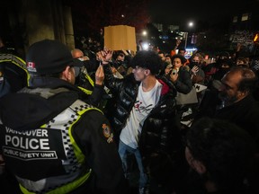 A man who was taking part in a demonstration in support of Palestine has handcuffs removed and is released after being detained by police officers, in Vancouver, on Thursday, Oct. 19, 2023. Vancouver police say the Israel-Hamas war has fuelled hate crimes in the city and sparked far more protests than usual, where policing for the emotional events has cost millions.
