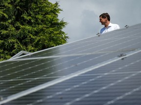 B.C. Premier David Eby walks past a solar panel array at the Tsleil-Waututh Nation as he arrives for an announcement, in North Vancouver, B.C., on Thursday, June 15, 2023. Eby has announced a push to expand the province's electricity system that could see billions in extra spending on infrastructure projects.