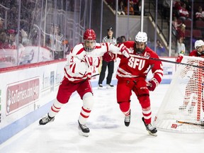 Liam Visram of SFU (in red jersey) and Devlin Kaplan of Boston University chase after a loose puck Friday in Boston.