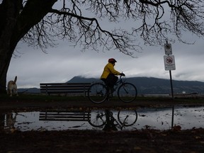 Environment Canada has downgraded a rainfall warning for parts of Metro Vancouver, but B.C.'s River Forecast Centre has added a flood watch for the Sumas area as a series of atmospheric rivers deluge the province's South Coast. A person rides their bicycle in the rain at Locarno Beach in Vancouver, B.C., Saturday, Nov. 11, 2023.