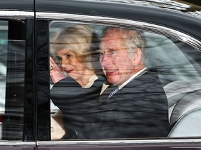 King Charles III and Queen Camilla wave as they leave by car from Clarence House, travelling to Buckingham Palace, in London on February 6, 2024. King Charles III's estranged son Prince Harry reportedly arrived in London on Tuesday after his father's diagnosis of cancer, which doctors "caught early."