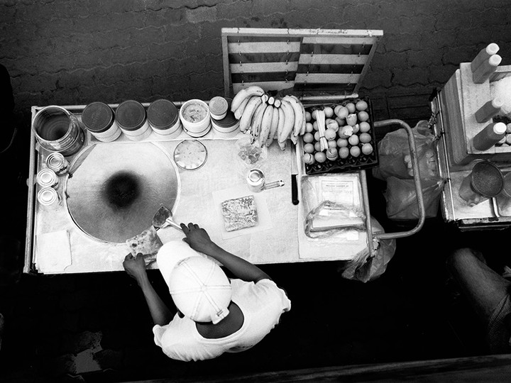  A street vendor prepares banana pancakes (a favourite sweet snack) from his stall.