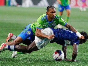 Seattle Sounders midfielder Léo Chú falls over Vancouver Whitecaps midfielder Richie Laryea during the first half of an MLS soccer match Saturday, Oct. 7, 2023, in Seattle.