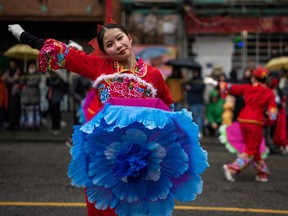 A girl dances with a blue flower umbrella during the 50th annual Spring Festival Parade for the Lunar New Year in Vancouver, B.C., Sunday, Feb. 11, 2024.