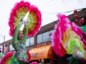 A dancer moves through the street while waving colourful fans during the 50th annual Spring Festival Parade through Chinatown for the Lunar New Year in Vancouver, B.C., Sunday, Feb. 11, 2024.