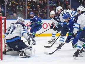 Vancouver Canucks' Pius Suter puts a shot wide of the net behind Winnipeg Jets goalie Connor Hellebuyck during the first period of an NHL game in Vancouver February 17, 2024.