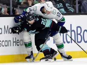 Kraken right wing Oliver Bjorkstrand battles with Tyler Myers for the puck during Thursday's game in Seattle.