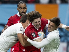 Argentina's Santiago Alvarez, left, and Marcos Moneta, right, tackle Canada's David Richard as Josiah Morra watches from behind during Vancouver Sevens rugby action, in Vancouver, on Friday, Feb. 23, 2024.