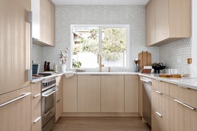 In the kitchen, rift-cut oak cabinetry mingles with mixed metals, and a soft blue-grey backsplash – Trapezoid Tile from Cepac via Daltile – creating a calming palette, and highly functional cooking space for the home's six inhabitants.