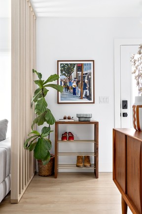 To define the home's entrance, which opens into the middle of the living room, designer Lori Steeves added a slatted divider wall, which suits the mid-century esthetic of the house. Muuto Dot wall hooks –purchased from Gabriel Ross – and a custom walnut console-shoe shelf by Enrique Morales of Madera Fina Studio Furniture provide storage in the absence of a front closet.