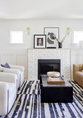 The living room fireplace got a fresh face of new tile (Geode by Andy Fleishman Field Tiles) and stylish lighting (Hindsdale-1 sconces by Hudson Valley Lighting) to complement furniture pieces and artwork reflecting the owners' love of midcentury and eclectic style.