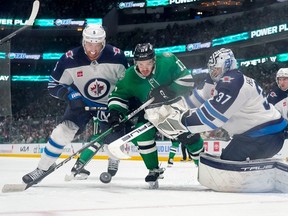 Logan Stankoven #11 of the Dallas Stars compete for the puck against Brenden Dillon #5 and Connor Hellebuyck #37 of the Winnipeg Jets during the third period at American Airlines Center on February 29, 2024 in Dallas, Texas.