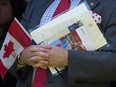 A new Canadian holds a Canadian flag at a 2019 citizenship ceremony.