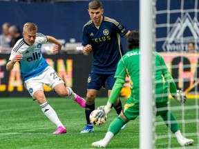 Charlotte FC's Jere Uronen tries to score on Vancouver Whitecaps goalkeeper Yohei Takaoka as Ranko Veselinovic watches during the first half in Vancouver, on Saturday, Mar. 2, 2024.