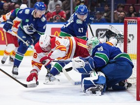 Calgary Flames' Andrei Kuzmenko (96) is upended after being stopped by Vancouver Canucks goalie Casey DeSmith (29) as Noah Juulsen (47) and Nikita Zadorov (91) watch during the first period of an NHL hockey game in Vancouver, on Saturday, March 23, 2024.