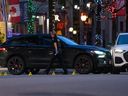 Un policier de Vancouver passe devant un SUV noir entouré de cônes de preuves après avoir fermé une partie de la rue Robson en raison d'une fusillade à Vancouver, samedi 30 mars.  30, 2024.