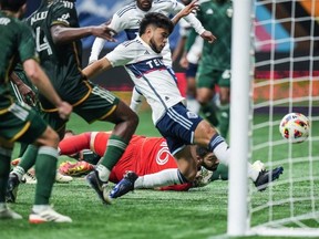 Portland Timbers goalkeeper Maxime Crepeau, back centre, watches as Vancouver Whitecaps' Ryan Raposo scores during the MLS match, in Vancouver, on Saturday, March 30, 2024.