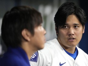 Los Angeles Dodgers' designated hitter Shohei Ohtani, right, chats with his interpreter Ippei Mizuhara during an exhibition baseball game between Team Korea and the Los Angeles Dodgers at the Gocheok Sky Dome in Seoul, South Korea, Monday, March 18, 2024.