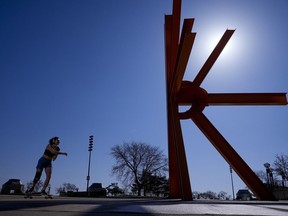 A woman skateboards near a sculpture as she enjoys unseasonably warm weather, Feb. 27, 2024, in Milwaukee. Earth has exceeded global heat records in February, according to the European Union climate agency Copernicus.