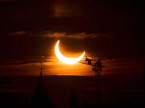 An annular solar eclipse rises over construction cranes and the Peace Tower on Parliament Hill in Ottawa on Thursday, June 10, 2021. A total solar eclipse is a rare celestial event that always generates excitement, but next month's version is expected to be unusually spectacular.