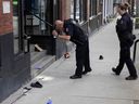 Un policier de Vancouver surveille les lieux sur la rue Cambie, entre Smithe et Robson, à la suite d'une grave agression au couteau survenue le mercredi 20 mars 2024. Plusieurs objets, dont un couteau et une torche au butane, étaient visibles sur le trottoir.