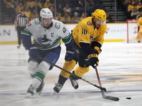 Colton Sissons of the Predators tries to keep the puck from Quinn Hughes of the Vancouver Canucks at Bridgestone Arena on Dec. 19, 2023, in Nashville. The Canucks won 5-2.