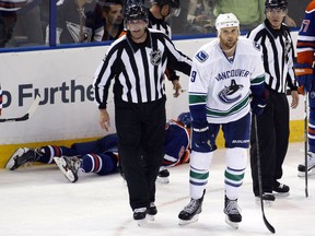 Vancouver Canucks Zack Kassian gets escorted to the penalty box after being whistled for high-sticking Edmonton's Sam Gagner's in their 2013 game. Kassian was later suspended for five games, as his stickwork had broken Gagner's jaw and expelled several teeth.
