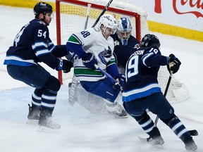 Winnipeg Jets goaltender Laurent Brossoit (39) saves the shot from Vancouver Canucks' Nils Aman (88) as Dylan Samberg (54) and David Gustafsson (19) defend during first period NHL action in Winnipeg on Thursday, April 18, 2024.