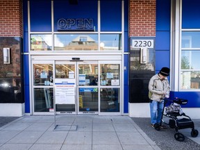 A woman waits outside of the London Drugs Broadway and Vine location in Vancouver on Monday, April 29, 2024.