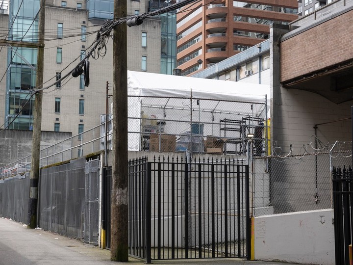  A tent being erected in the parking lot of a social housing building in the 1000-block Howe Street as seen from the alley