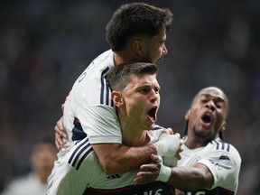 Vancouver Whitecaps' Ranko Veselinovic, front centre, Ryan Raposo, back left, and Levonte Johnson celebrate Veselinovic's goal against Toronto FC during second half MLS soccer action in Vancouver, B.C., Saturday, April 6, 2024.