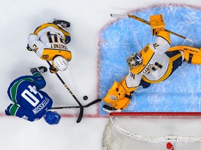 Elias Pettersson shoots on goaltender Juuse Saros and Spencer Stastney during the first period of Game 1.