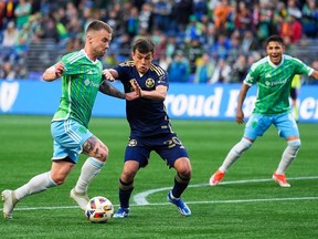 Seattle Sounders midfielder Albert Rusnák drives toward the goal against Vancouver Whitecaps midfielder Andrés Cubas, as Sounders forward Raúl Ruidíaz watches during MLS soccer match  May 18, 2024, in Seattle.