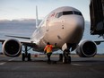 A ground worker approaches a WestJet Airlines Boeing 737 Max aircraft after it arrived at Vancouver International Airport in Richmond, B.C., on Thursday, January 21, 2021. WestJet has issued a 72-hour lockout notice to the union representing its mechanics, and warns a work stoppage could happen as early as Tuesday.