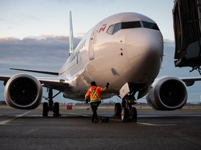 A ground worker approaches a WestJet Airlines Boeing 737 Max aircraft after it arrived at Vancouver International Airport in Richmond, B.C., on Thursday, January 21, 2021. WestJet has issued a 72-hour lockout notice to the union representing its mechanics, and warns a work stoppage could happen as early as Tuesday.