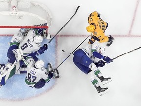 Vancouver Canucks goaltender Arturs Silovs, J.T. Miller, Ian Cole and Tyler Myers defend the goal against Nashville Predators' Ryan O'Reilly during the third period in Game 6 of an NHL hockey Stanley Cup first-round playoff series Friday, May 3, 2024, in Nashville, Tenn.