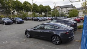 Dozens of unsold new Teslas sit behind a fence in a parking lot in Langley this week.