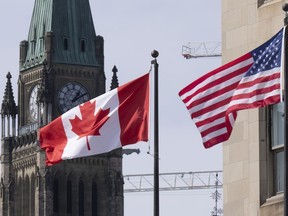 Canadian and U.S. flags are seen flying near Parliament Hill in Ottawa.