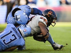 B.C. Lions running back William Stanback (31) dives with the ball while being tackled by Toronto Argonauts defensive back Leonard Johnson (13) and linebacker Wynton McManis (48) during the first half