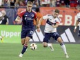 New England Revolution midfielder Noel Buck (29) and Vancouver Whitecaps midfielder Ryan Gauld (25) chase the ball during the second half of an MLS soccer match Saturday, June 15, 2024, in Foxborough, Mass.