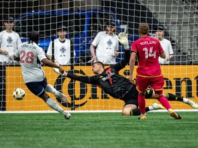 Vancouver Whitecaps' Levonte Johnson is stopped by St. Louis City goalkeeper Ben Lundt as Tomas Totland  watches during MLS match in Vancouver June 29, 2024.
