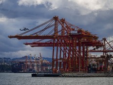 A BC Ambulance Service helicopter operated by Helijet passes gantry cranes used to load and unload cargo ships at port while preparing to land, in Vancouver, on Thursday, July 25, 2024. The BC Maritime Employers Association says it has been told by a lawyer for the port foremen's union that an industry-wide strike vote will take place in coming weeks.