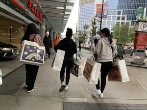 Shoppers carry bags from the Aritzia Warehouse Sale Friends & Family day on Aug. 26, 2024. The sale runs Aug. 27 through Sept. 2 at the Vancouver Convention Centre West.
